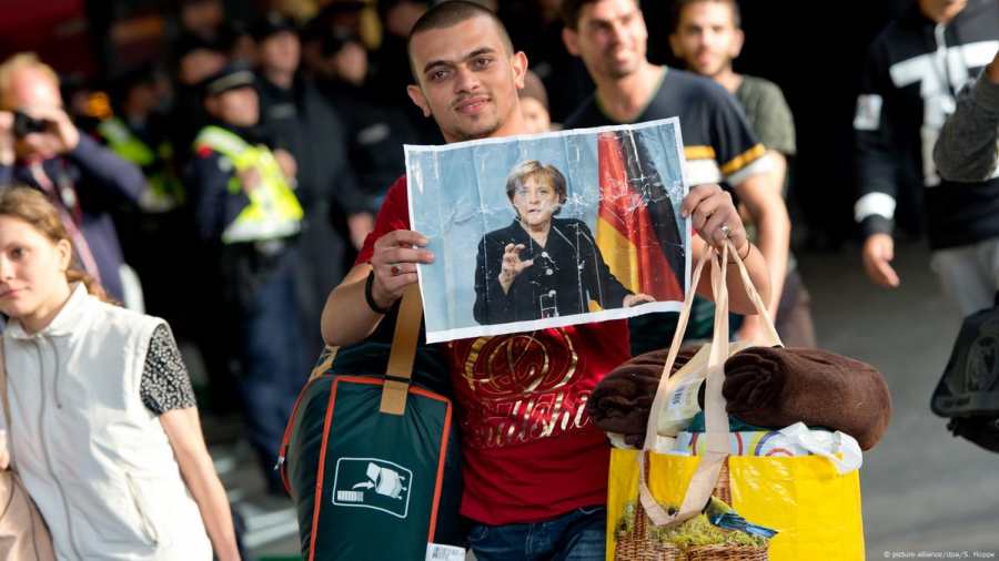 Kiemelt képen: egy migráns Angela Merkel képét tartja maga előtt Németországban / Fotó: picture-alliance/dpa/S. Hoppe