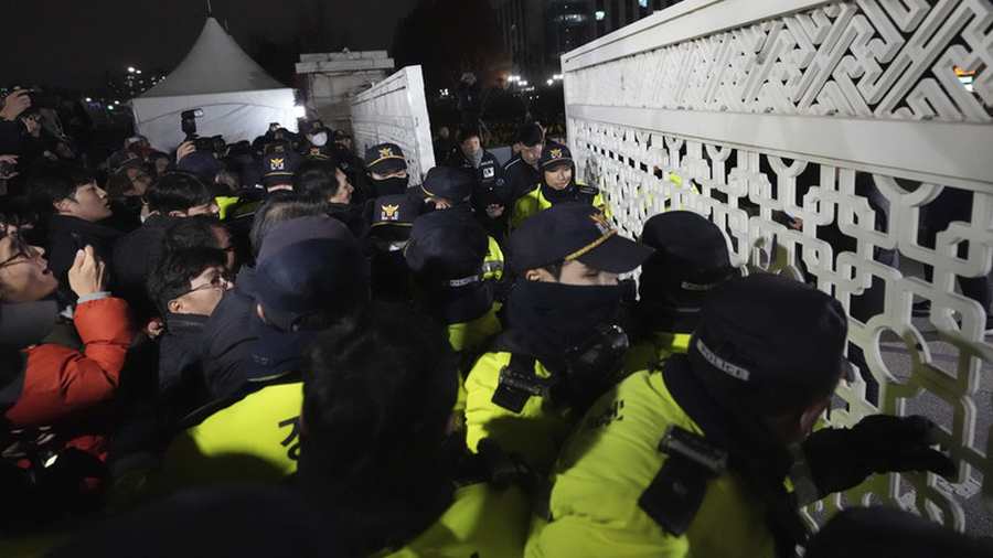 2024. december 3-án, kedden az emberek megpróbálnak bejutni, a dél-koreai Szöulban, a nemzetgyűlés épületébe, ahol rendőrök őrködnek / Fotó: © AP Photo/Lee Jin-man