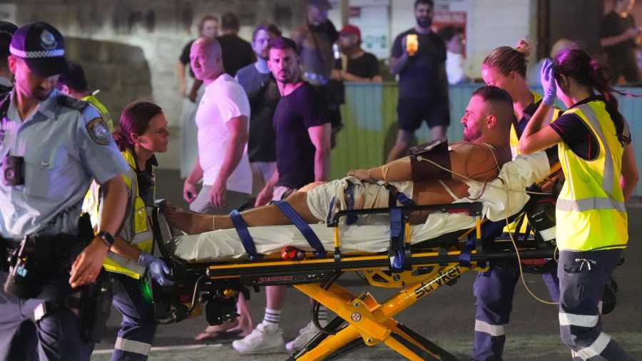 Kiemelt kép: Sebesültet visznek kórházba mentősök Sydney Bondi Beach nevű tengerparti strandjáról, ahol ismeretlen fegyveresek lelőttek kilenc embert, sokakat megsebesítettek 2025. december 14-én (Fotó: MTI/AP/Mark Baker)