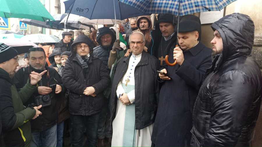 Hívek imádkoznak a nagyváradi premontrei templom előtt az esőben